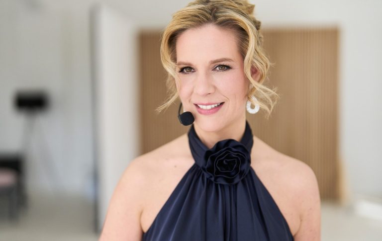 Feines Gespür und Charme – Moderation von Natascha Enders Natascha Enders trägt ein elegantes, schwarzes Oberteil und ein Mikrofon.