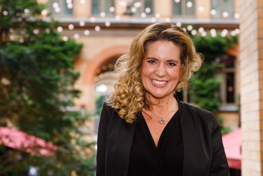 Preisverleihungen moderieren – Natascha Enders Natascha Enders im Außenbereich vor Backsteinbögen – Portrait für Preisverleihungen